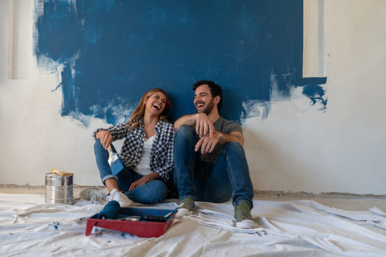 Happy couple laughing while taking a break from painting